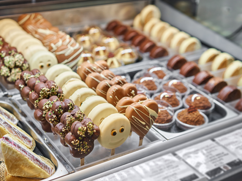 Photo of chocolate lollipops and muffins in bakery shop display