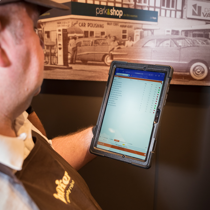 A store operative using Cybake ISB in-store production planning software on a tablet device