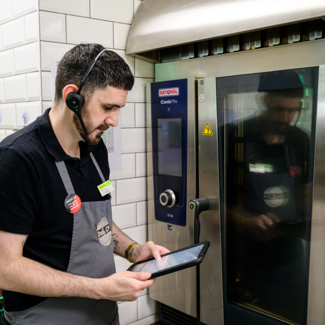Photo of a store associate at Co op using Cybake ISB food preparation instructions on a tablet